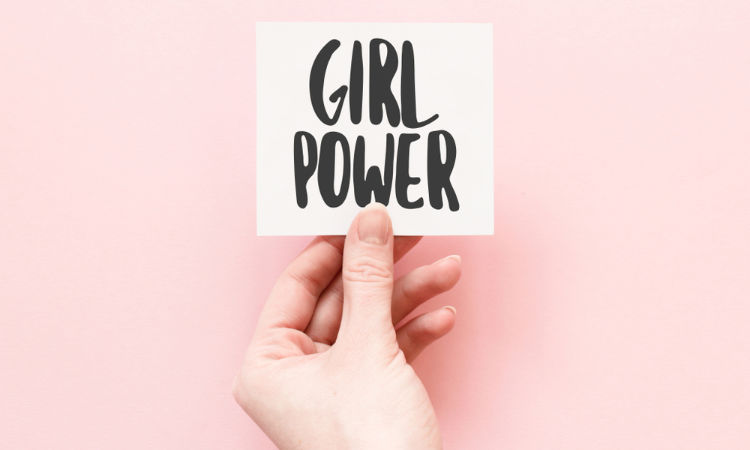 Eine Hand hält ein Karte, auf der Girl Power zu lesen ist